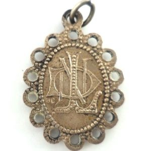 Reverse side of silver-plated Our Lady of Lourdes medal with monogram "ND."