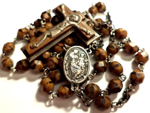 Close-up of antique rosary with brown banded agate beads, silver crucifix, and central medal.