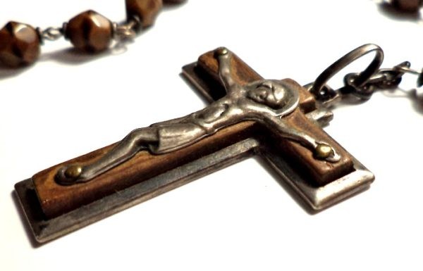 Close-up of antique rosary with brown banded agate beads, silver crucifix, and central medal.