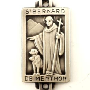 Close-up of an antique silverplated Saint Bernard of Menthon medal, featuring the saint and a St. Bernard dog with a mountainous background.